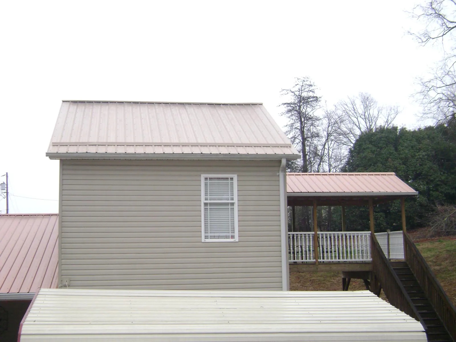 Tan metal roofs on a two story addition and attached porch, from a Roof Replacement job in Woodland